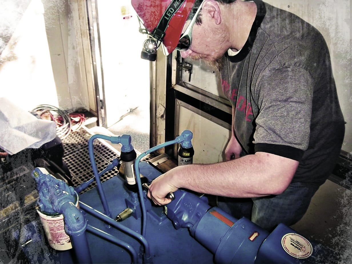 A lube tech attending to a machine in the field.